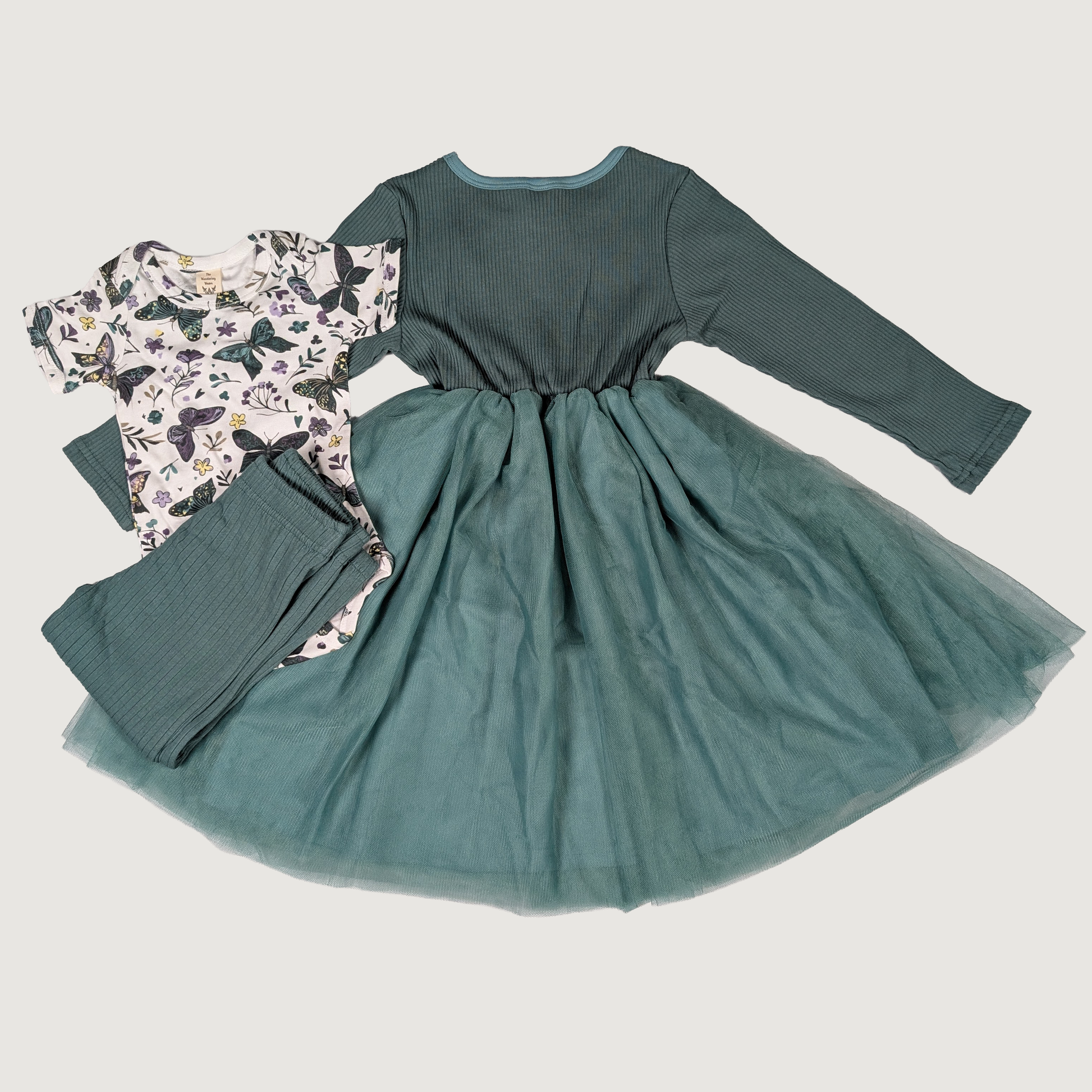 Green dress with long sleeves and floral patterned pants on a light gray background